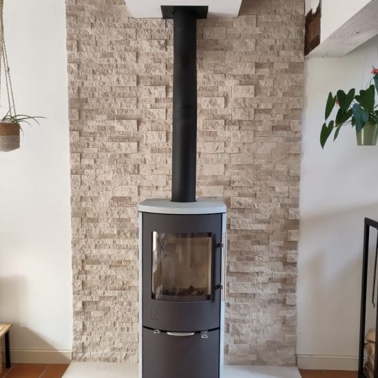 Parement travertin en intérieur avec un poêle